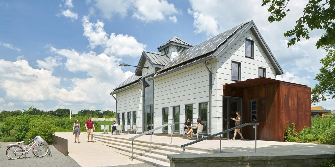 波胆网站的学生们走过伊甸园大厅校园里屋顶上安装着太阳能电池板的白色奶牛棚.