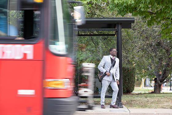 一名男子等公共汽车的照片，一辆模糊的公共汽车驶入画面
